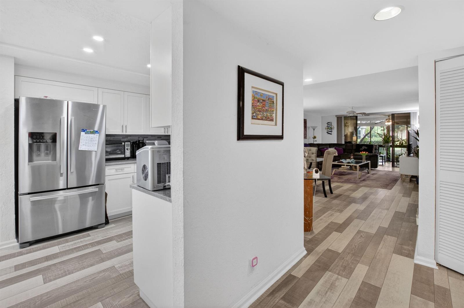 A view from a kitchen area looking into a living room with wood-look flooring — 7254 Clunie Place # 15002, Delray Beach FL 33446, DELRAY BEACH, FL