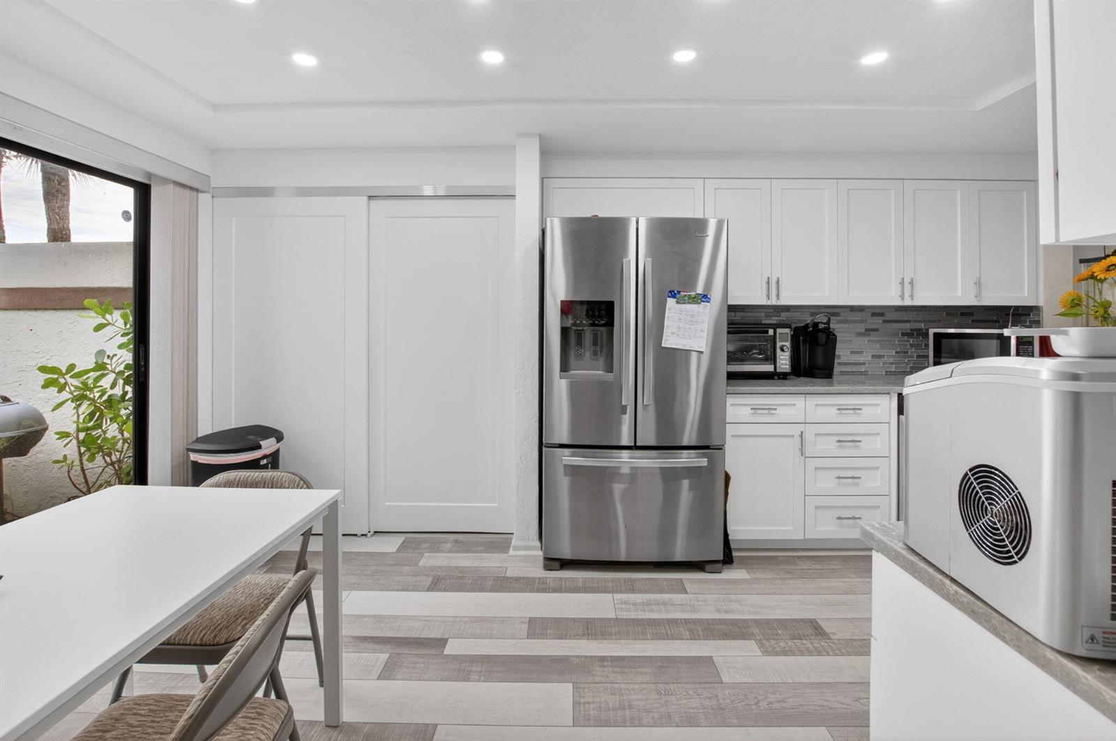 A kitchen with white cabinets, stainless steel appliances, and wood-look tile flooring — 7254 Clunie Place # 15002, Delray Beach FL 33446, DELRAY BEACH, FL
