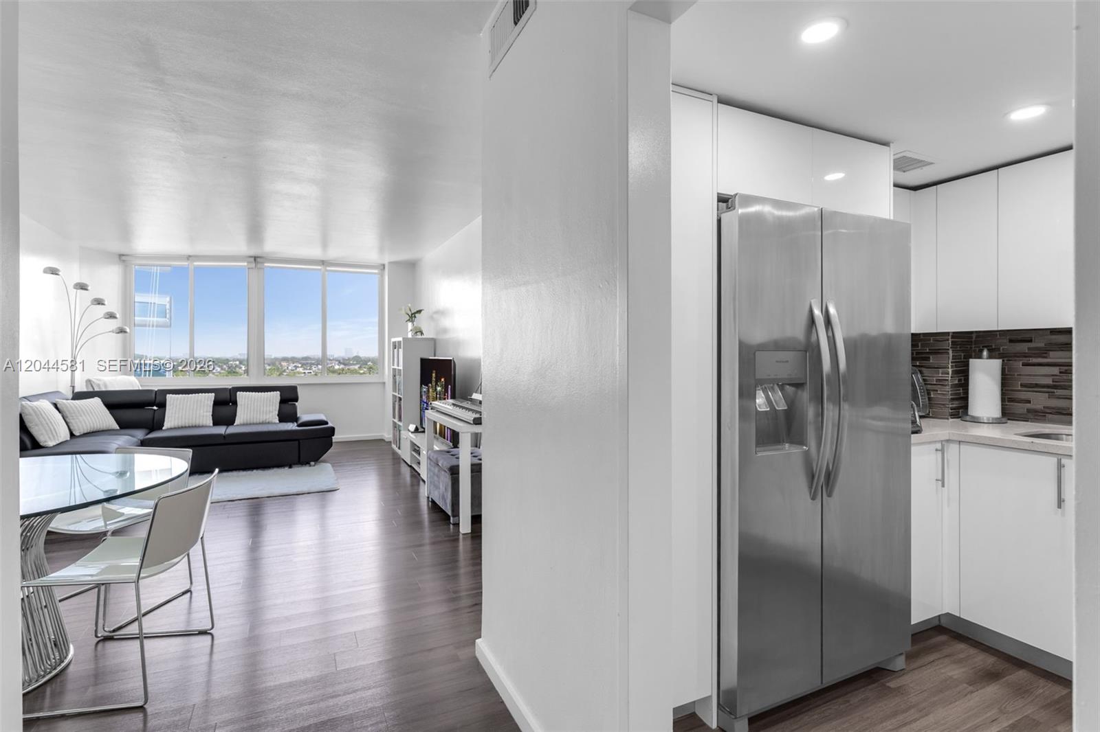 A modern apartment features an open-concept living area with dark wood floors and a kitchen — 7441 Wayne Ave # 10H, Miami Beach FL 33141, MIAMI BEACH, FL