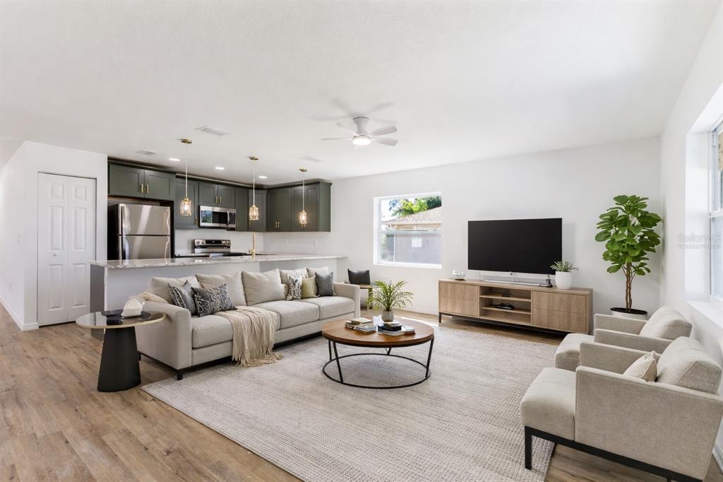 A living room with a beige sofa, two armchairs, a coffee table, and an open kitchen — 6254 SPINNAKER BOULEVARD, ENGLEWOOD, FL