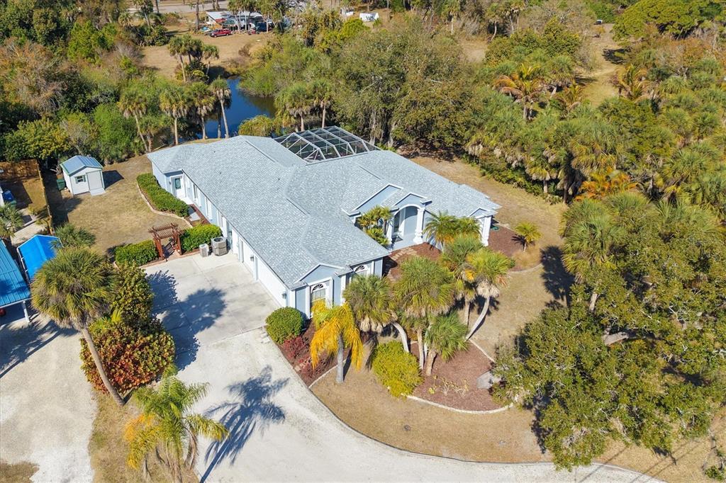 An aerial view shows a single-story house with a screened pool enclosure and palm trees — 750 HARMONY LANE, ENGLEWOOD, FL