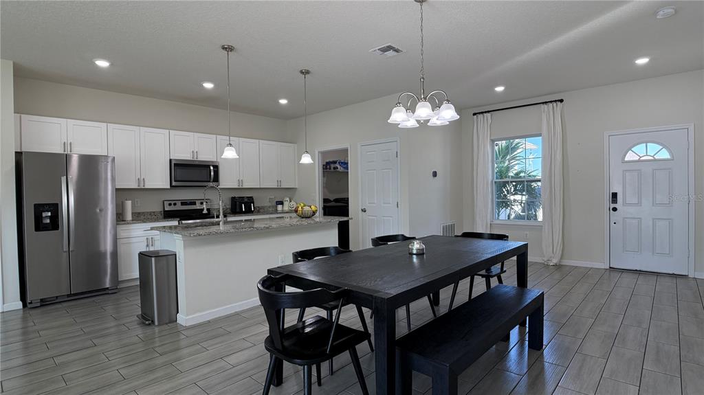 A kitchen and dining area with white cabinets, granite countertops, and a dark wood table — 2129 HIBISCUS PLACE, POINCIANA, FL
