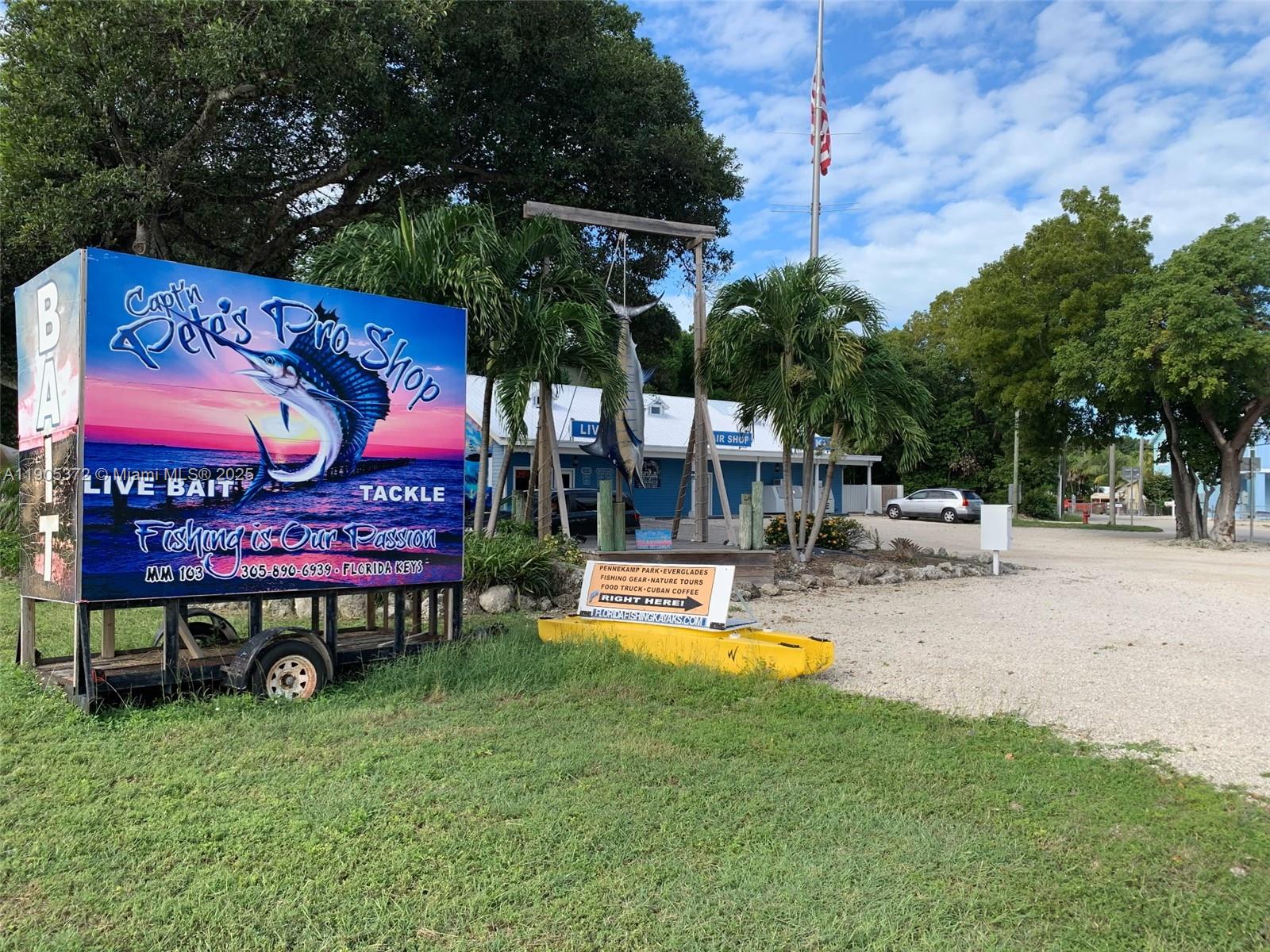 A large sign for a fishing pro shop stands on a trailer near a building — 102970 Overseas Hwy, Key Largo FL 33037, KEY LARGO, FL
