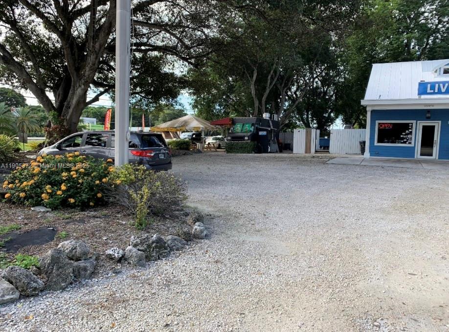A gravel parking lot sits in front of a blue building and a food truck — 102970 Overseas Hwy, Key Largo FL 33037, KEY LARGO, FL