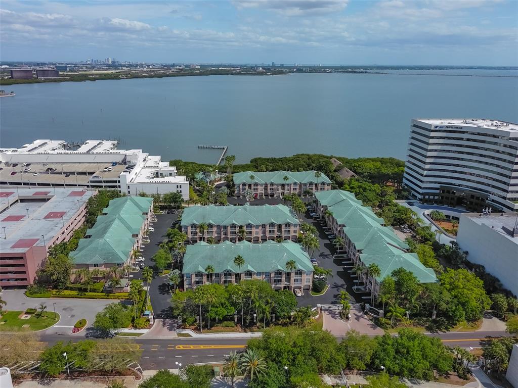 An aerial view shows a multi-building residential complex with green roofs near a large bay — 3205 BAY CLUB CIRCLE UNIT 3205, TAMPA, FL
