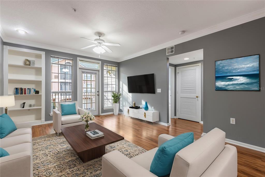 A living room features gray walls, hardwood floors, a television, and a white ceiling fan — 3205 BAY CLUB CIRCLE UNIT 3205, TAMPA, FL