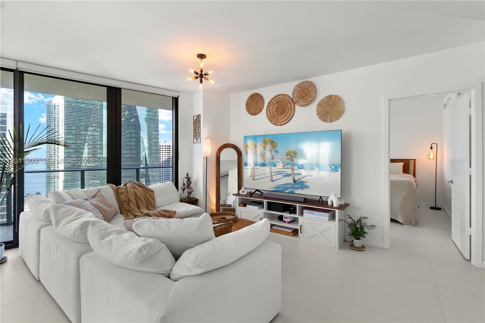 A bright living room features a white sectional sofa, a television console, and city views — 1300 S Miami Ave # 2001, Miami FL 33130, MIAMI, FL