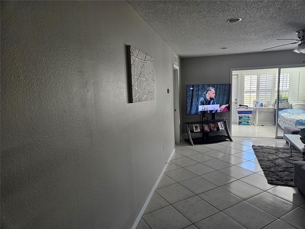 A living room features light-colored tile floors, a wall-mounted television, and a sliding glass door — 2900 GROVEWOOD BOULEVARD E UNIT C, PALM HARBOR, FL