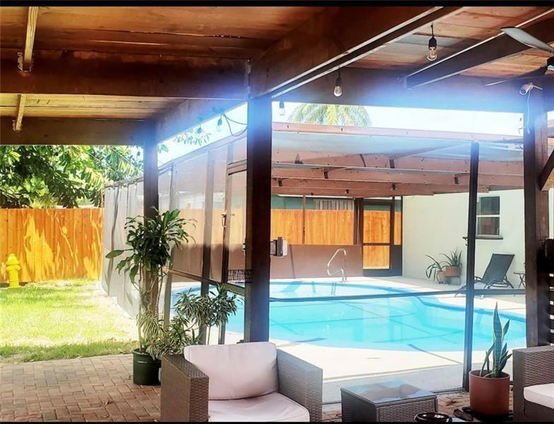 A covered patio overlooks a screened-in swimming pool and a fenced backyard — 5620 SW 56th Street, Davie FL 33314, DAVIE, FL