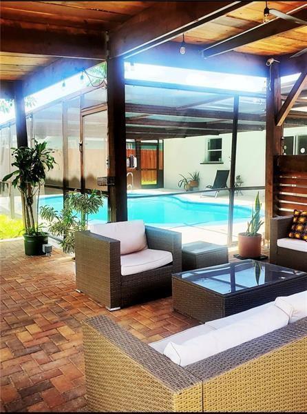 A covered patio with brick flooring overlooks a swimming pool enclosed by a screen — 5620 SW 56th Street, Davie FL 33314, DAVIE, FL