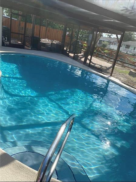 A screened-in swimming pool with steps and a metal handrail sits under a covered patio — 5620 SW 56th Street, Davie FL 33314, DAVIE, FL