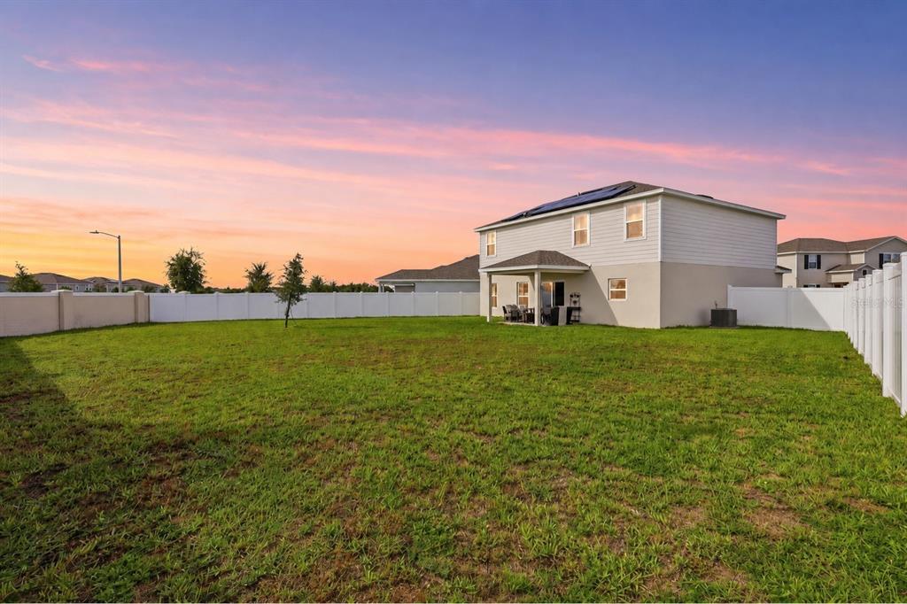 A two-story house with a covered patio and a large fenced backyard at sunset — 1141 LEXINGTON LANE, HAINES CITY, FL