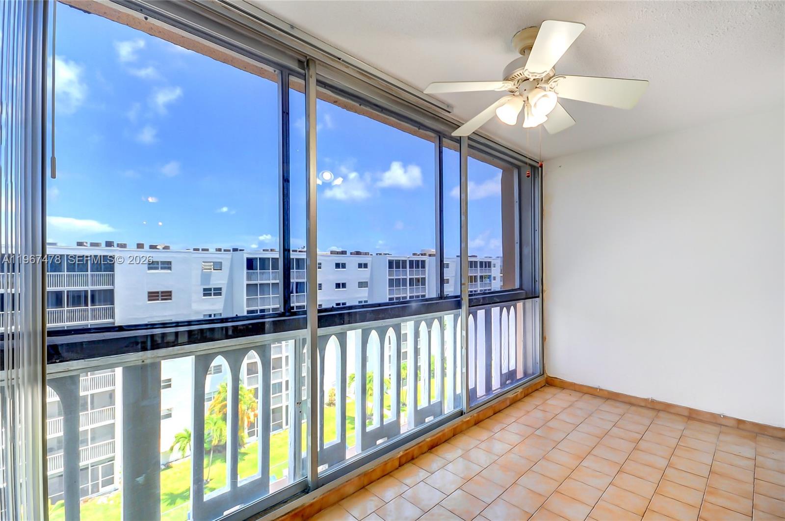 An enclosed balcony features tile flooring, a ceiling fan, and large sliding glass windows — 301 NE 14th Ave # 702, Hallandale Beach FL 33009, HALLANDALE BEACH, FL
