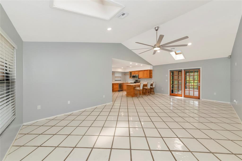 A spacious living area with light gray walls, white tiled floors, and a vaulted ceiling — 225 HOFFER STREET, PORT CHARLOTTE, FL