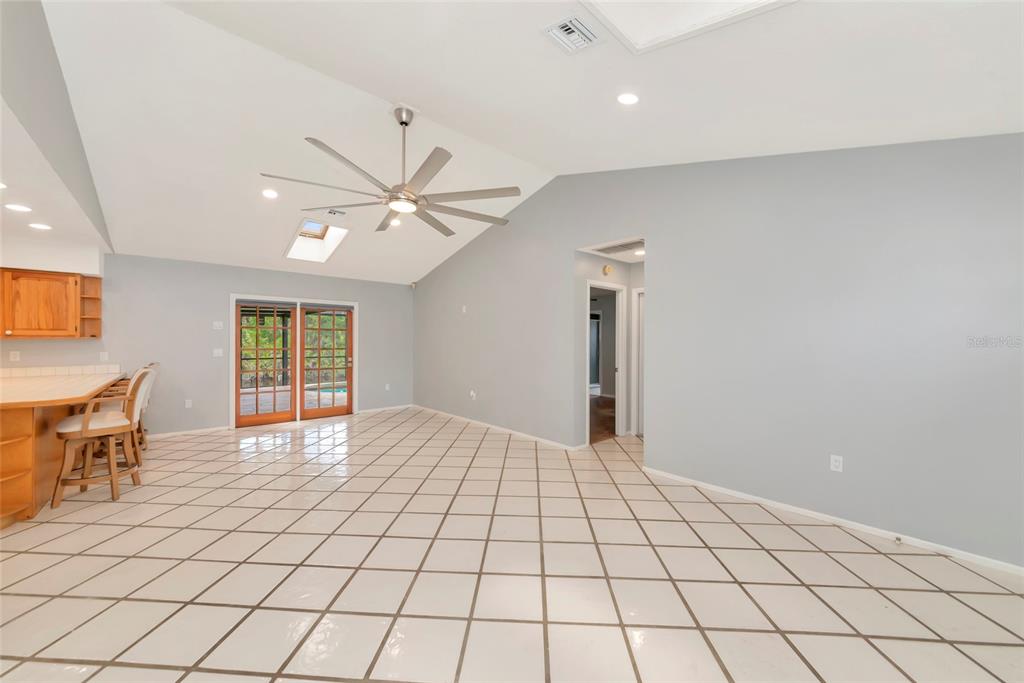 A spacious room with vaulted ceilings, tile flooring, a ceiling fan, and sliding glass doors — 225 HOFFER STREET, PORT CHARLOTTE, FL
