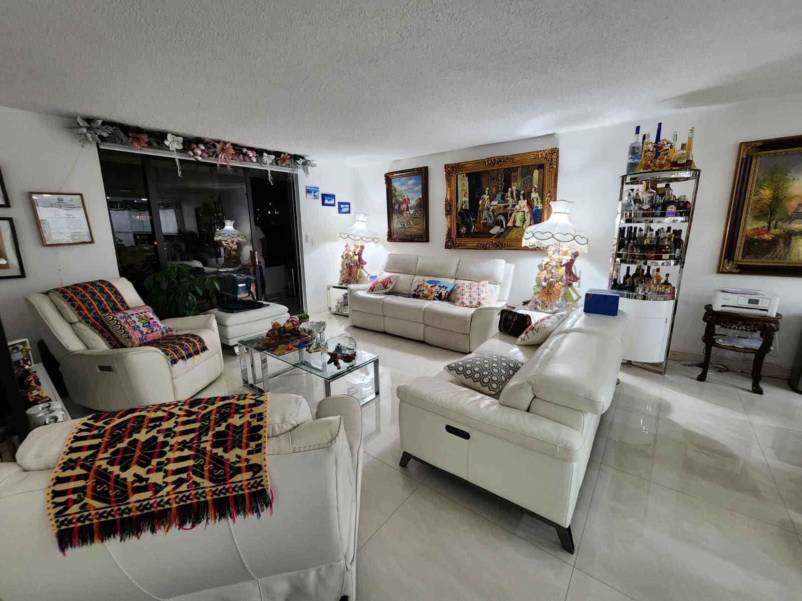 A bright living room features white leather sofas, a glass coffee table, and ornate lamps — 2500 Parkview Drive # 403, Hallandale Beach FL 33009, HALLANDALE BEACH, FL
