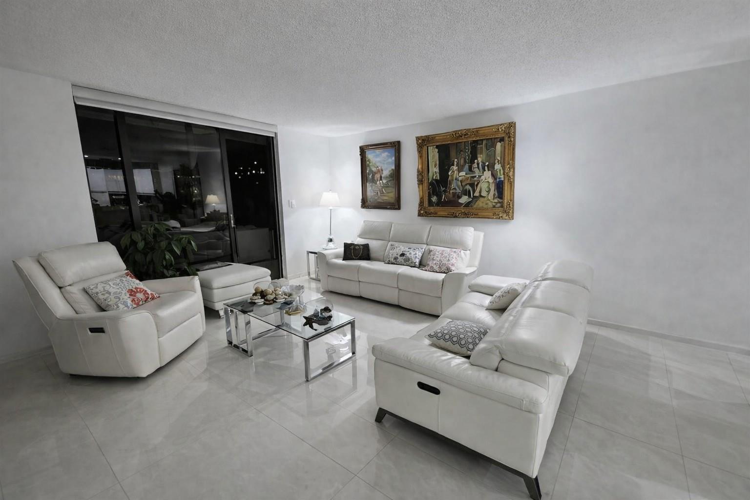 A living room features white leather sofas, a glass coffee table, and two framed paintings — 2500 Parkview Drive # 403, Hallandale Beach FL 33009, HALLANDALE BEACH, FL