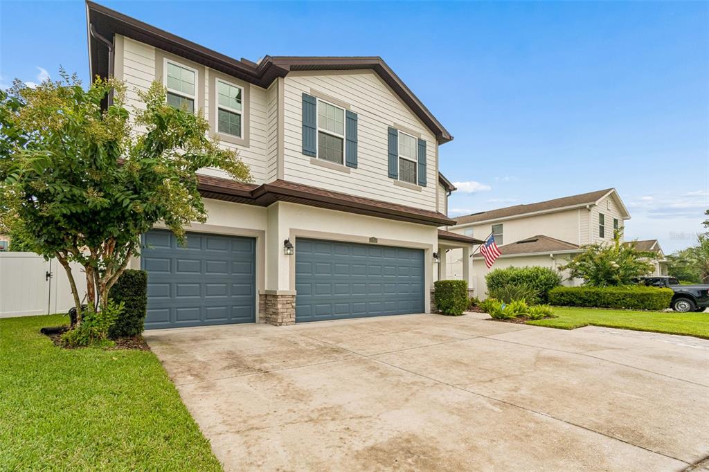 A two-story house with beige siding, a three-car garage, and a concrete driveway — 23958 TERRACINA COURT, LAND O LAKES, FL