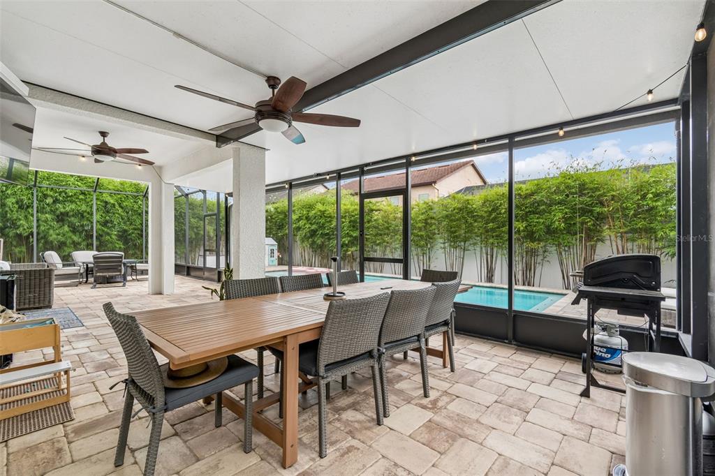 A covered outdoor patio features a dining set, ceiling fans, and a screened-in swimming pool — 23958 TERRACINA COURT, LAND O LAKES, FL