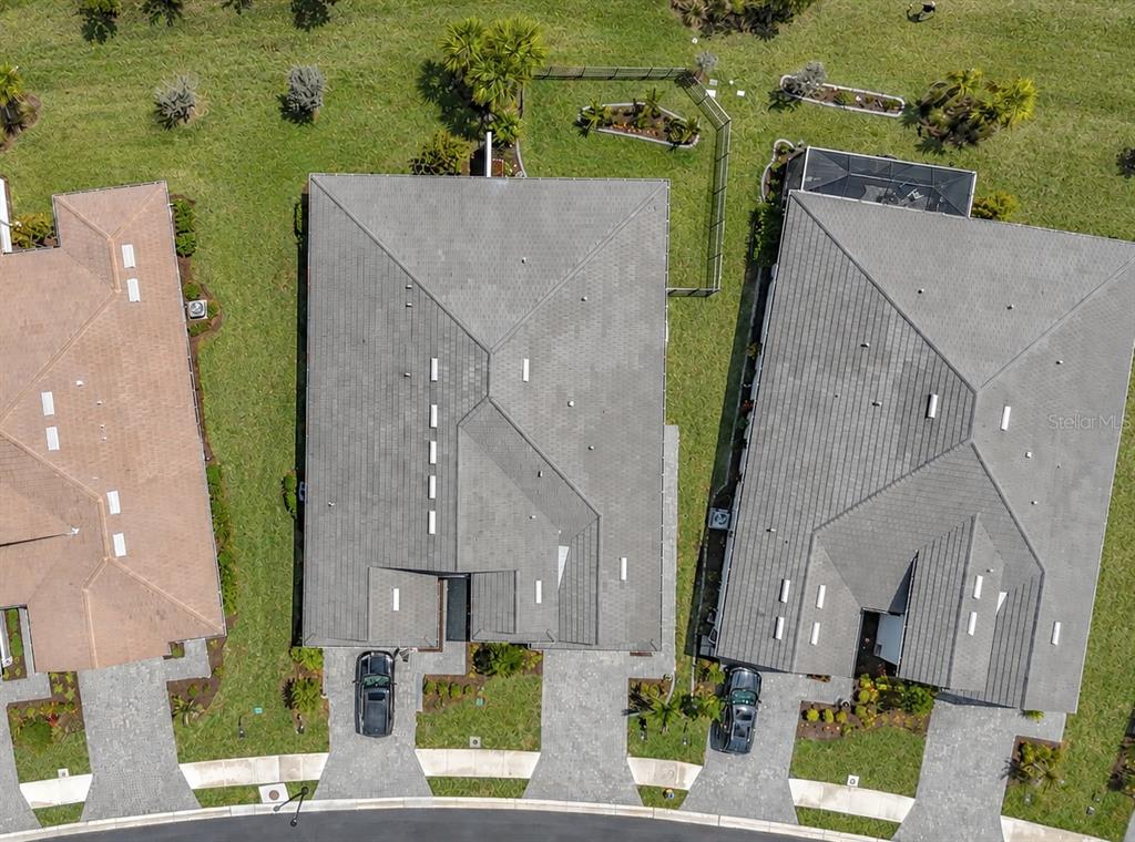 An aerial view shows three suburban houses with gray roofs and paved driveways — 18604 DAYSPRING PLACE, VENICE, FL