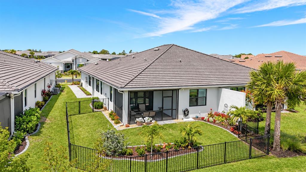 An aerial view shows the fenced backyard and screened patio of a suburban house — 18604 DAYSPRING PLACE, VENICE, FL
