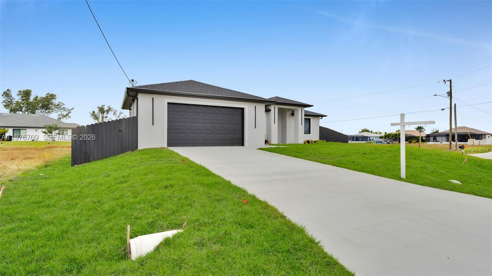 A modern single-story house with a dark garage door and a concrete driveway — 910 NW 36, Cape Coral FL 33993, CAPE CORAL, FL