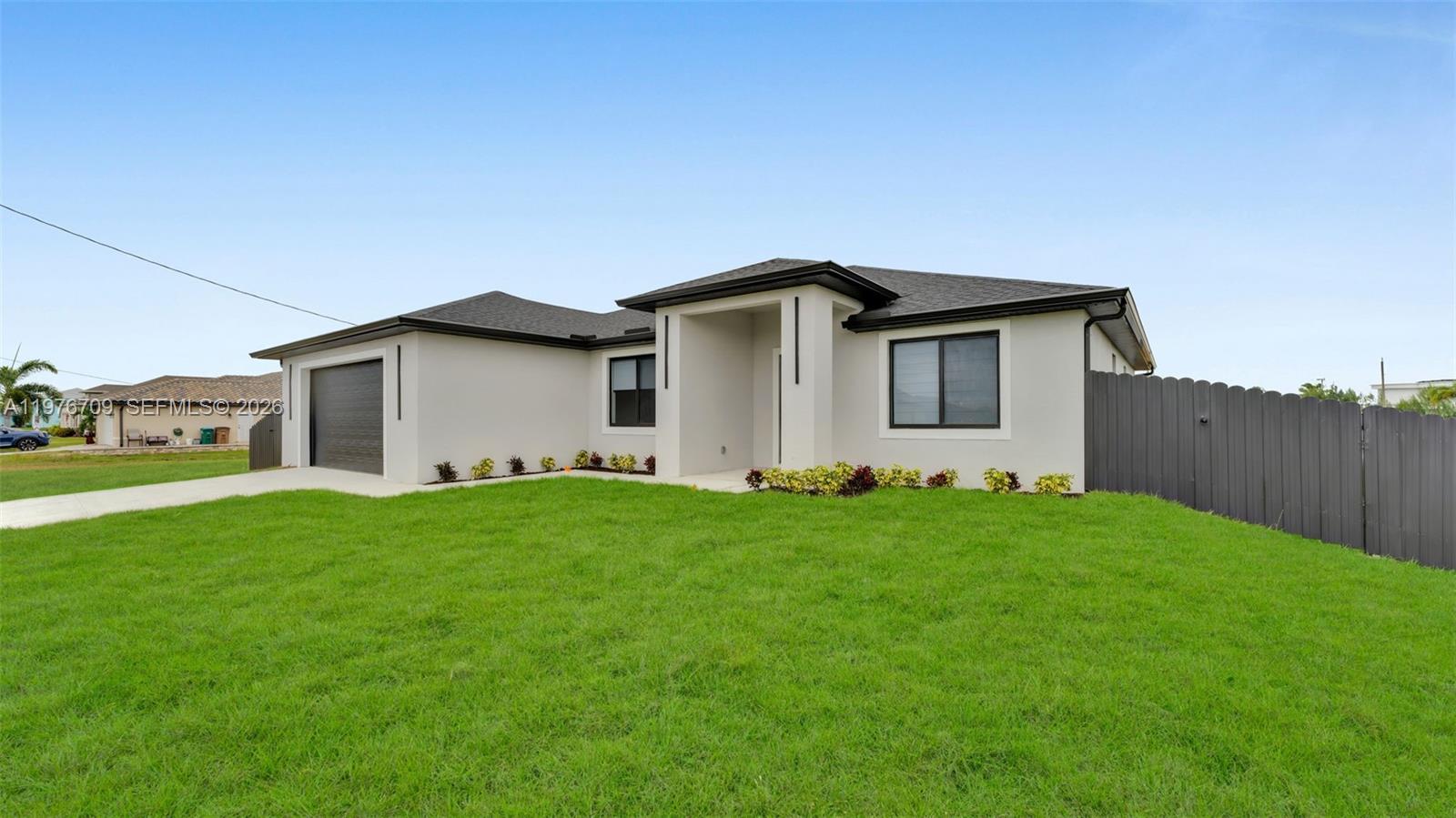 A single-story house with a garage, light-colored stucco walls, and a dark shingled roof — 910 NW 36, Cape Coral FL 33993, CAPE CORAL, FL