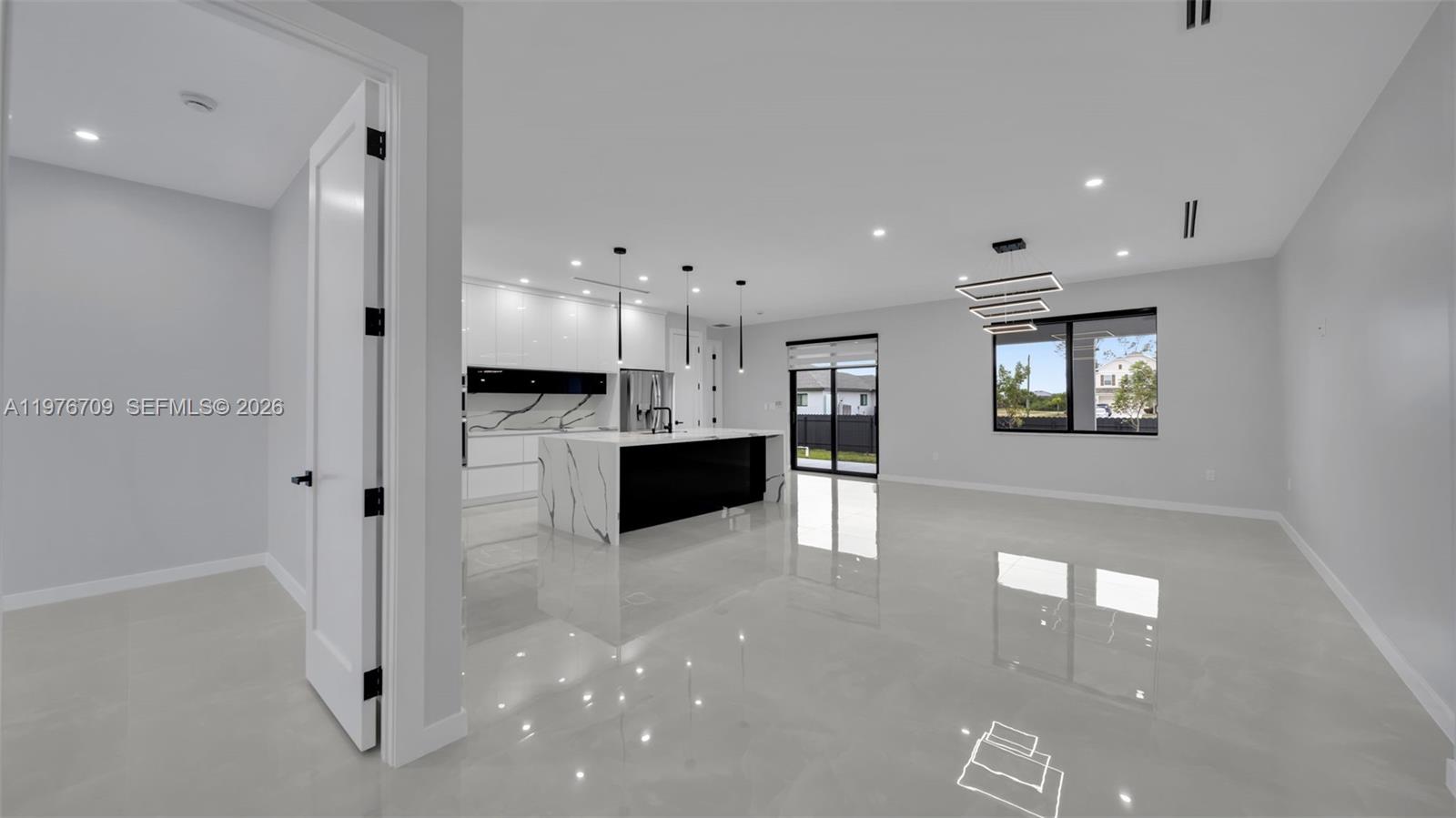 A modern kitchen with a black and white island sits in an open-concept living space — 910 NW 36, Cape Coral FL 33993, CAPE CORAL, FL