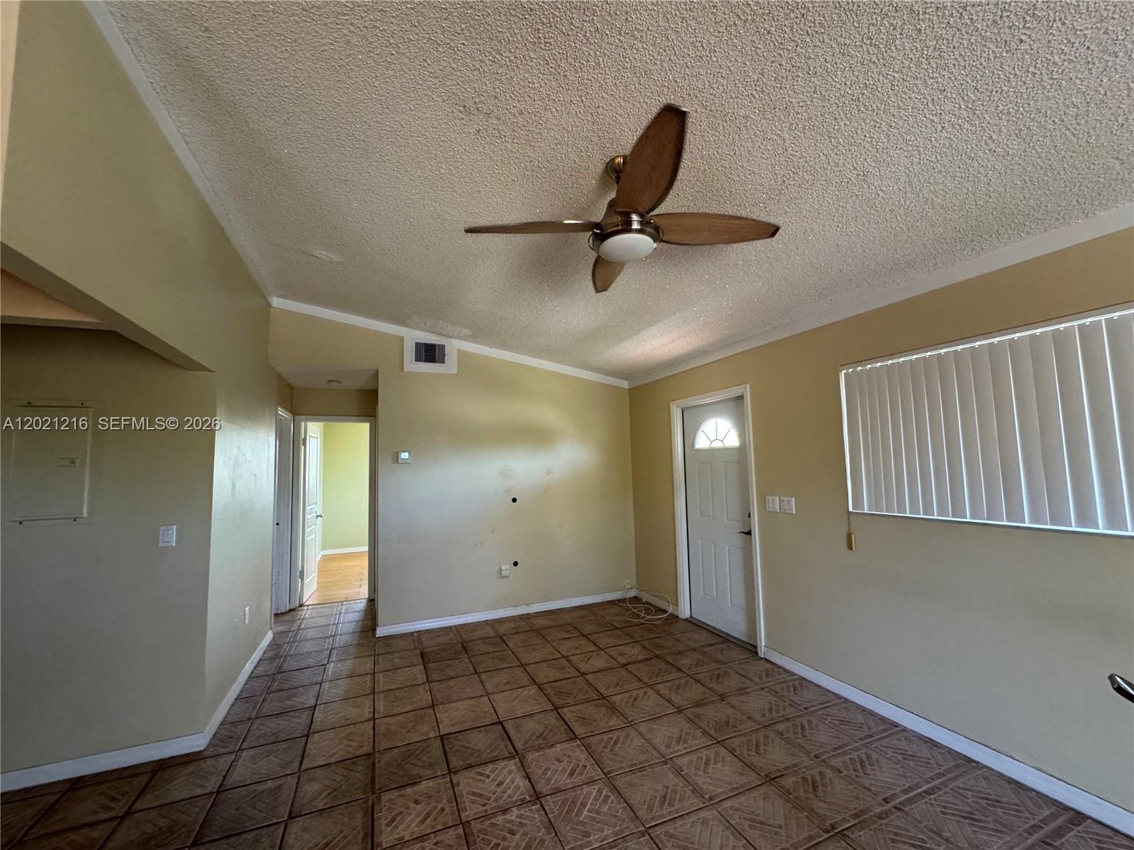 An empty room features tan walls, a popcorn ceiling with a fan, and tiled flooring — 104 Ocean Shores Drive, Key Largo FL 33037, KEY LARGO, FL