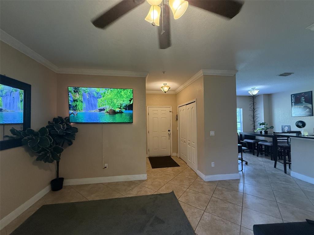 A living room with a wall-mounted television, tile flooring, and an entryway with white doors — 3721 S LAKE ORLANDO PARKWAY UNIT 3, ORLANDO, FL