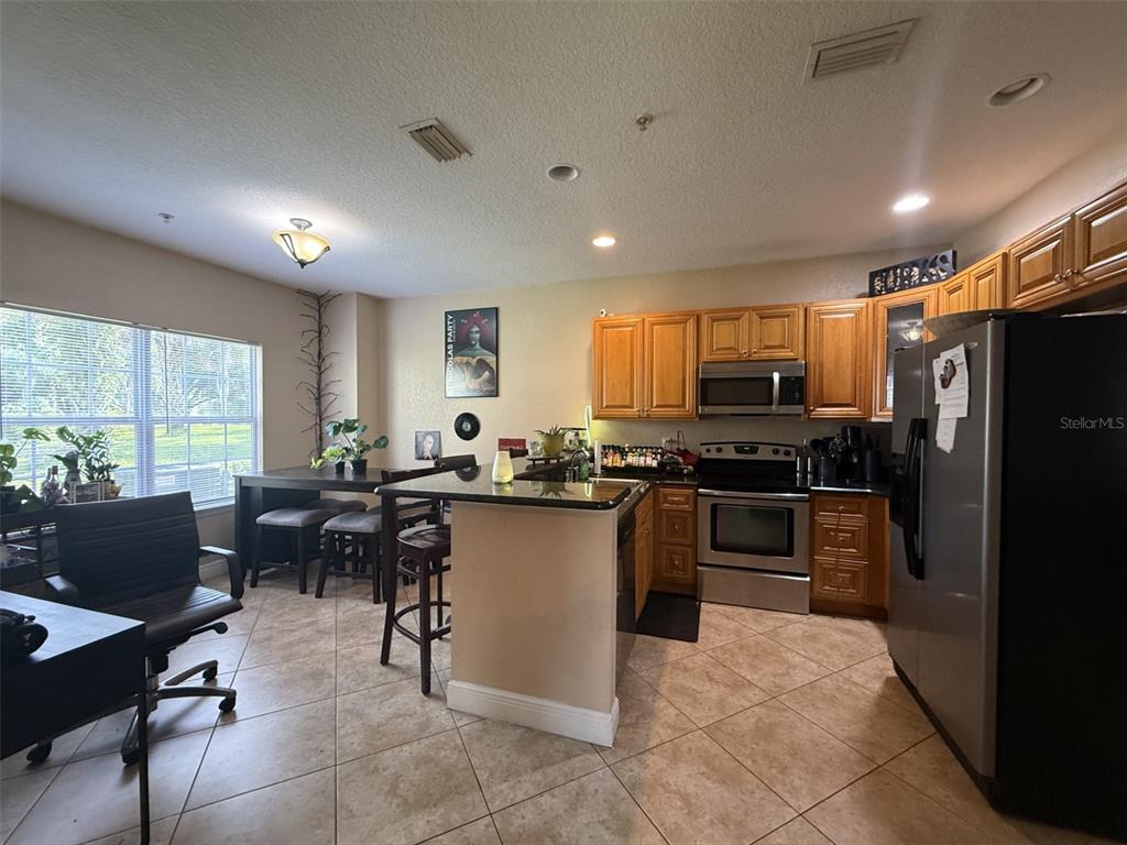 A kitchen with light wood cabinets, stainless steel appliances, and a small dining area — 3721 S LAKE ORLANDO PARKWAY UNIT 3, ORLANDO, FL