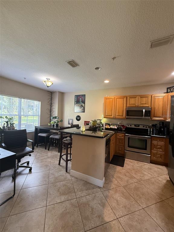 A kitchen with wood cabinets, stainless steel appliances, and a breakfast bar near a dining area — 3721 S LAKE ORLANDO PARKWAY UNIT 3, ORLANDO, FL