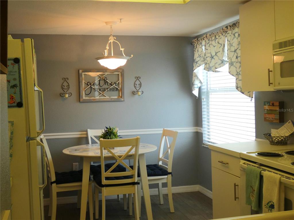 A kitchen dining area features a round table, white chairs, and a "gather" wall sign — 9320 CLUBSIDE CIRCLE UNIT 2208, SARASOTA, FL