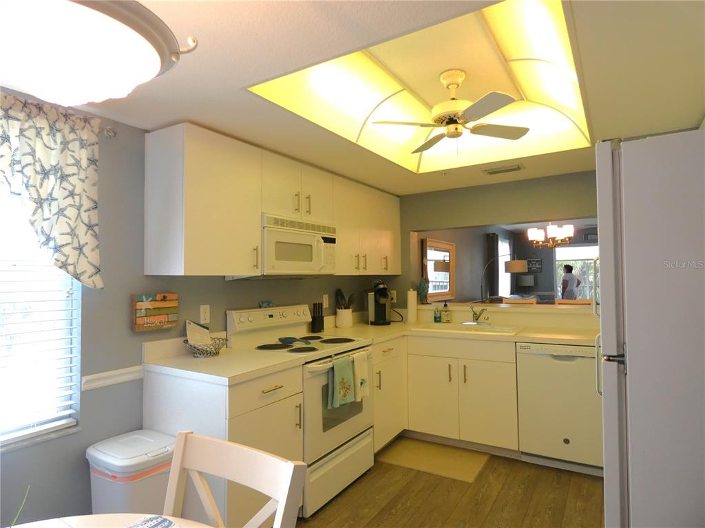 A kitchen with white cabinets, white appliances, a ceiling fan, and light wood-look flooring — 9320 CLUBSIDE CIRCLE UNIT 2208, SARASOTA, FL