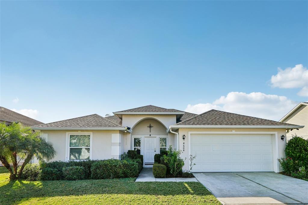 A single-story suburban house with a white garage, arched entryway, and landscaped front yard — 4604 SOUTHPORT BAY DRIVE, KISSIMMEE, FL