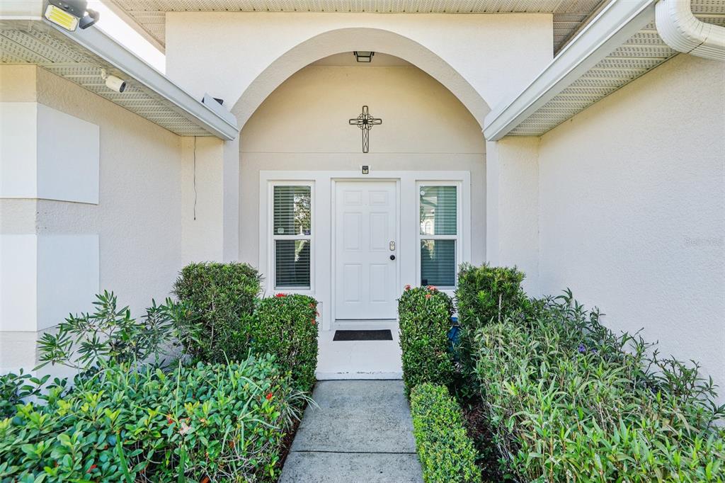 The exterior entrance features a white door, arched entryway, and surrounding green landscaping — 4604 SOUTHPORT BAY DRIVE, KISSIMMEE, FL