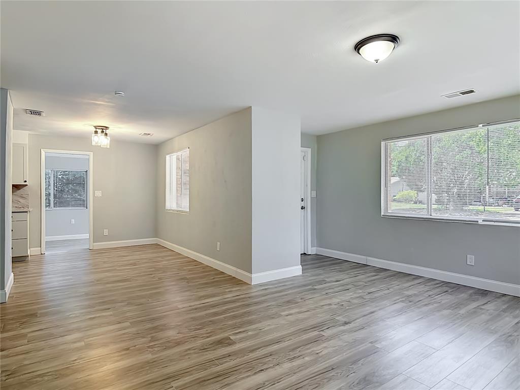 An open-concept living area features light gray walls, wood-look flooring, and a large window — 1495 GRANADA AVENUE, DAYTONA BEACH, FL