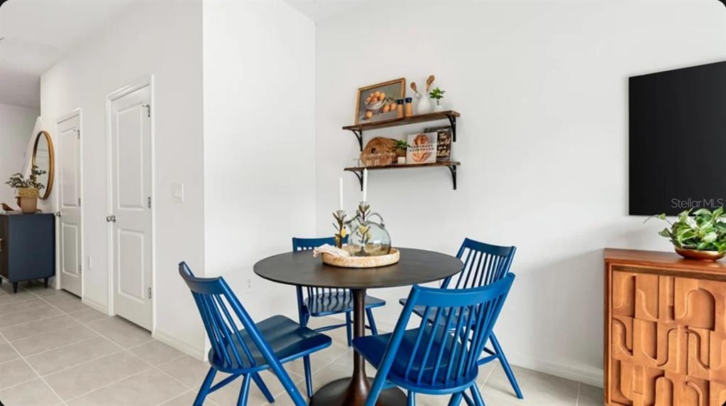 A dining area features a round table with four blue spindle chairs and wall shelving — 10778 ECLIPSE STREET, SARASOTA, FL