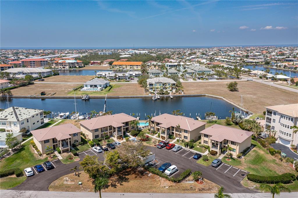 An aerial view shows multi-story apartment buildings with a parking lot and a canal — 3221 WHITE IBIS COURT UNIT D2, PUNTA GORDA, FL