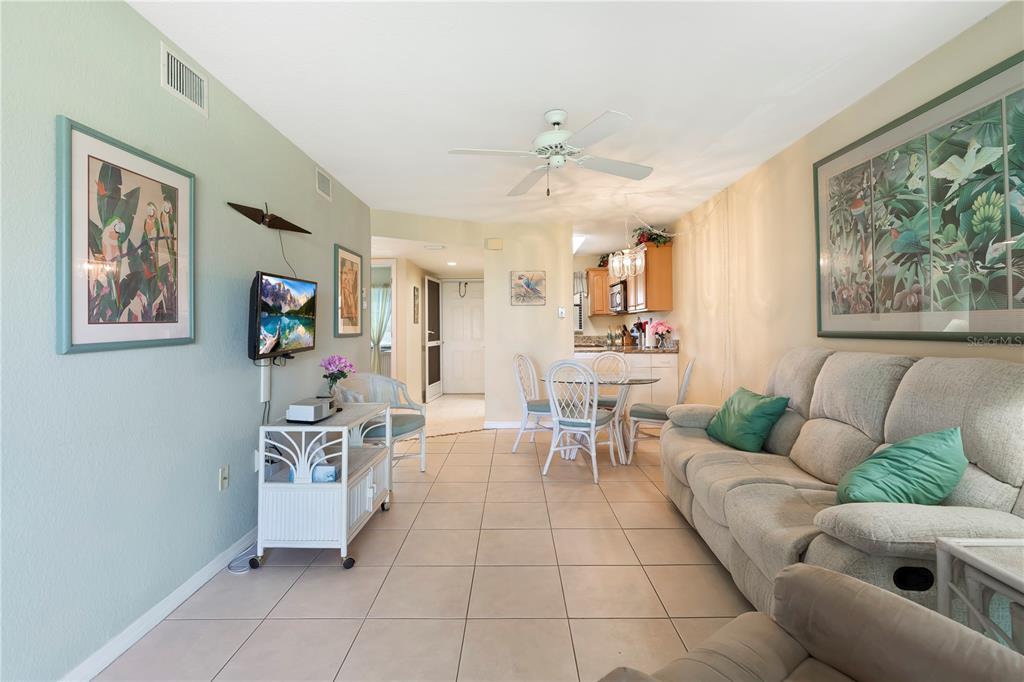 A living room with tile floors, a beige sofa, and an adjacent dining area — 3221 WHITE IBIS COURT UNIT D2, PUNTA GORDA, FL