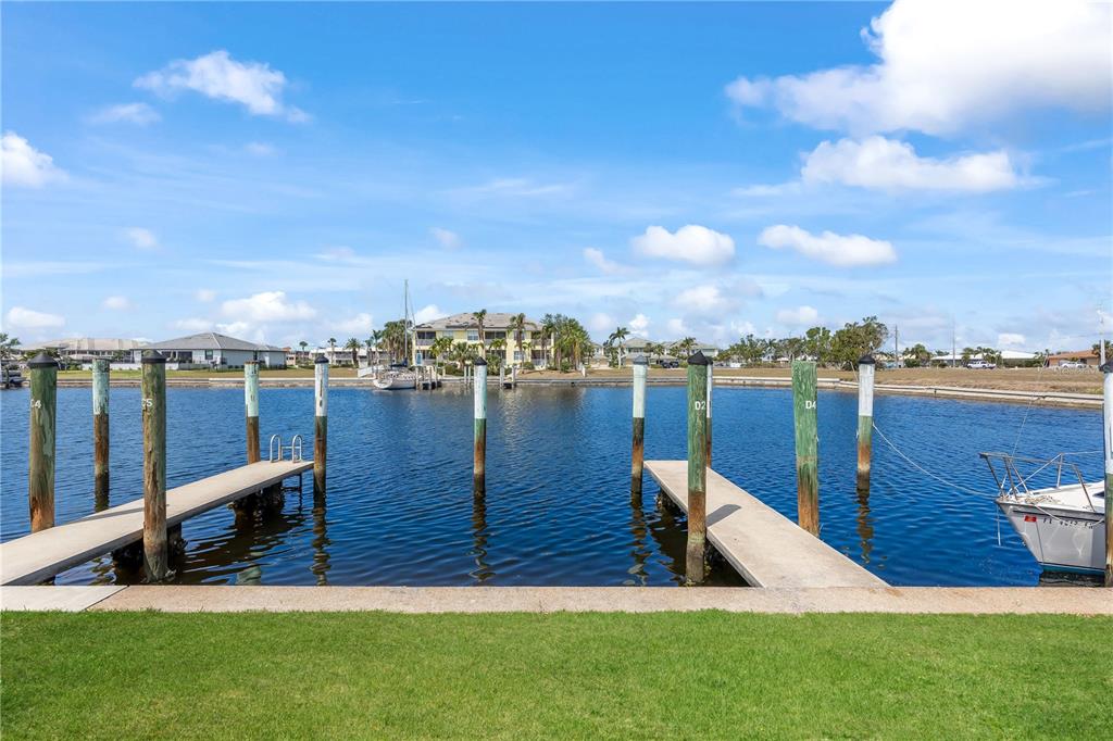 A view of a canal with two concrete boat docks and wooden pilings — 3221 WHITE IBIS COURT UNIT D2, PUNTA GORDA, FL