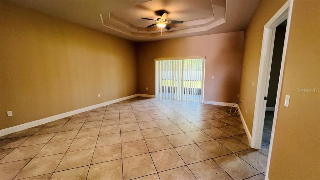 An open-concept kitchen with white cabinets and tile flooring flows into a large living area — 57 COLUMBIA LANE UNIT B, PALM COAST, FL