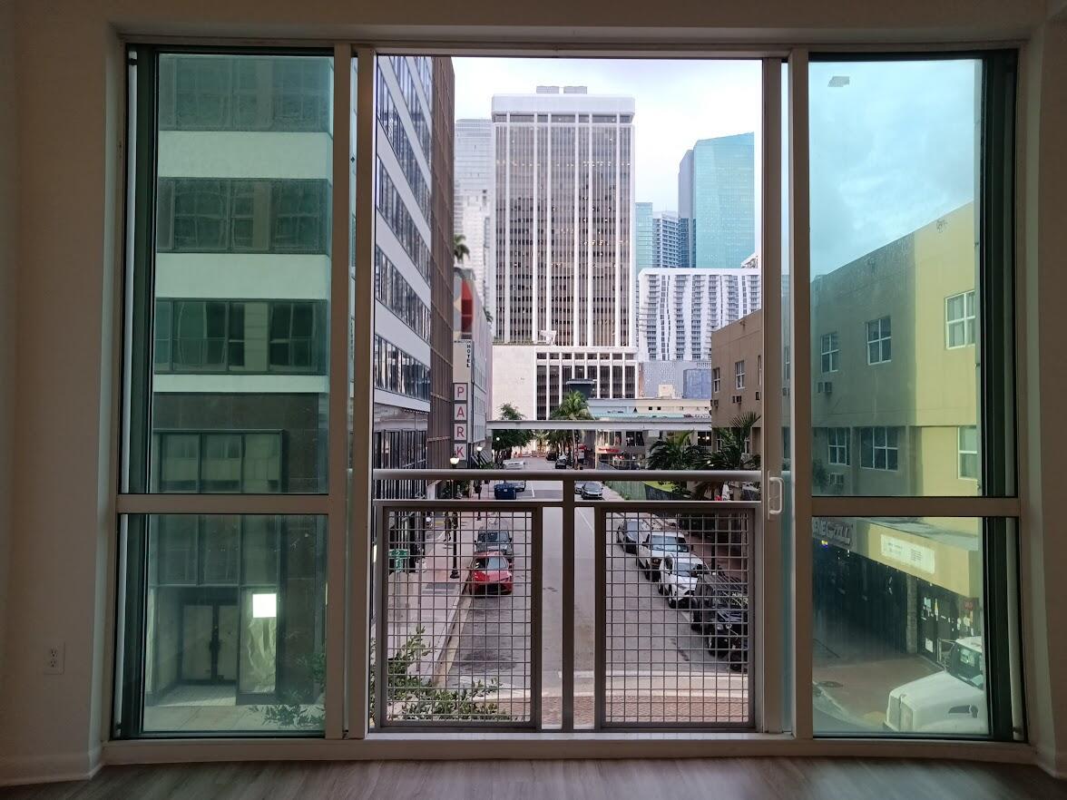A view of a city street and skyscrapers from inside a room through large windows — 253 NE 2nd Street # 221, Miami FL 33132, MIAMI, FL