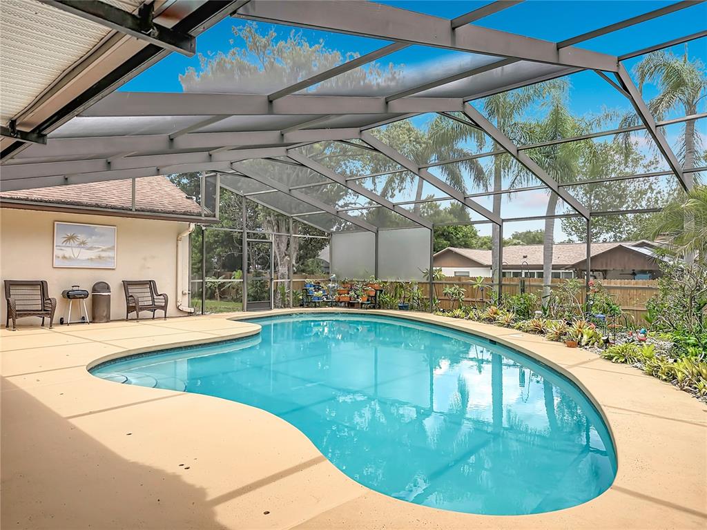A screened-in swimming pool with a tan concrete deck and patio furniture — 5427 SAGO PALM COURT, ORLANDO, FL