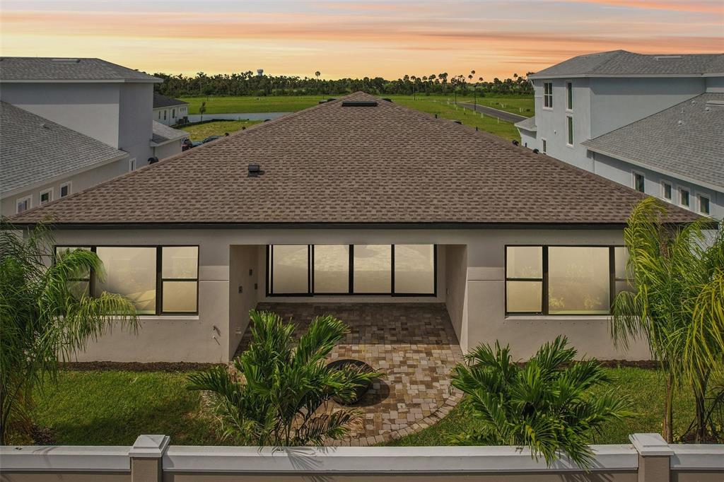 An exterior view of a house with a covered patio, paved area, and grassy backyard — 8320 GOLDEN BEACH COURT, PARRISH, FL