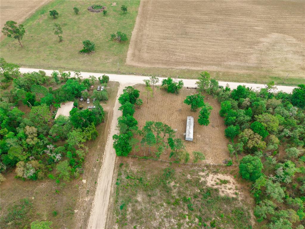 An aerial view shows a rural property with a dirt road, trees, and a small structure — 1390 NE 130TH AVENUE, WILLISTON, FL