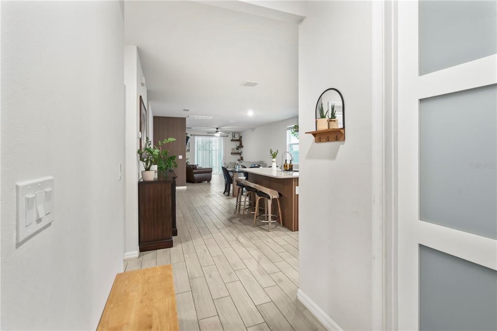 An entryway features a white door, frosted glass closet doors, a wooden bench, and wall decor — 551 AMADORAS WAY, ST CLOUD, FL