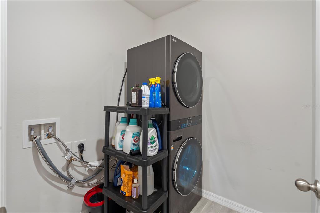 A modern kitchen features white cabinetry, a granite-topped island, stainless steel appliances, and tile flooring — 551 AMADORAS WAY, ST CLOUD, FL