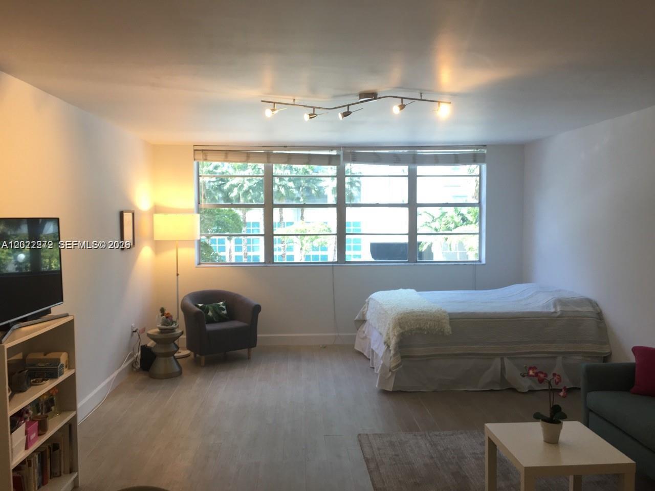A studio apartment with a bed, seating area, and large windows overlooking palm trees — 999 Brickell Bay Dr # 209, Miami FL 33131, MIAMI, FL