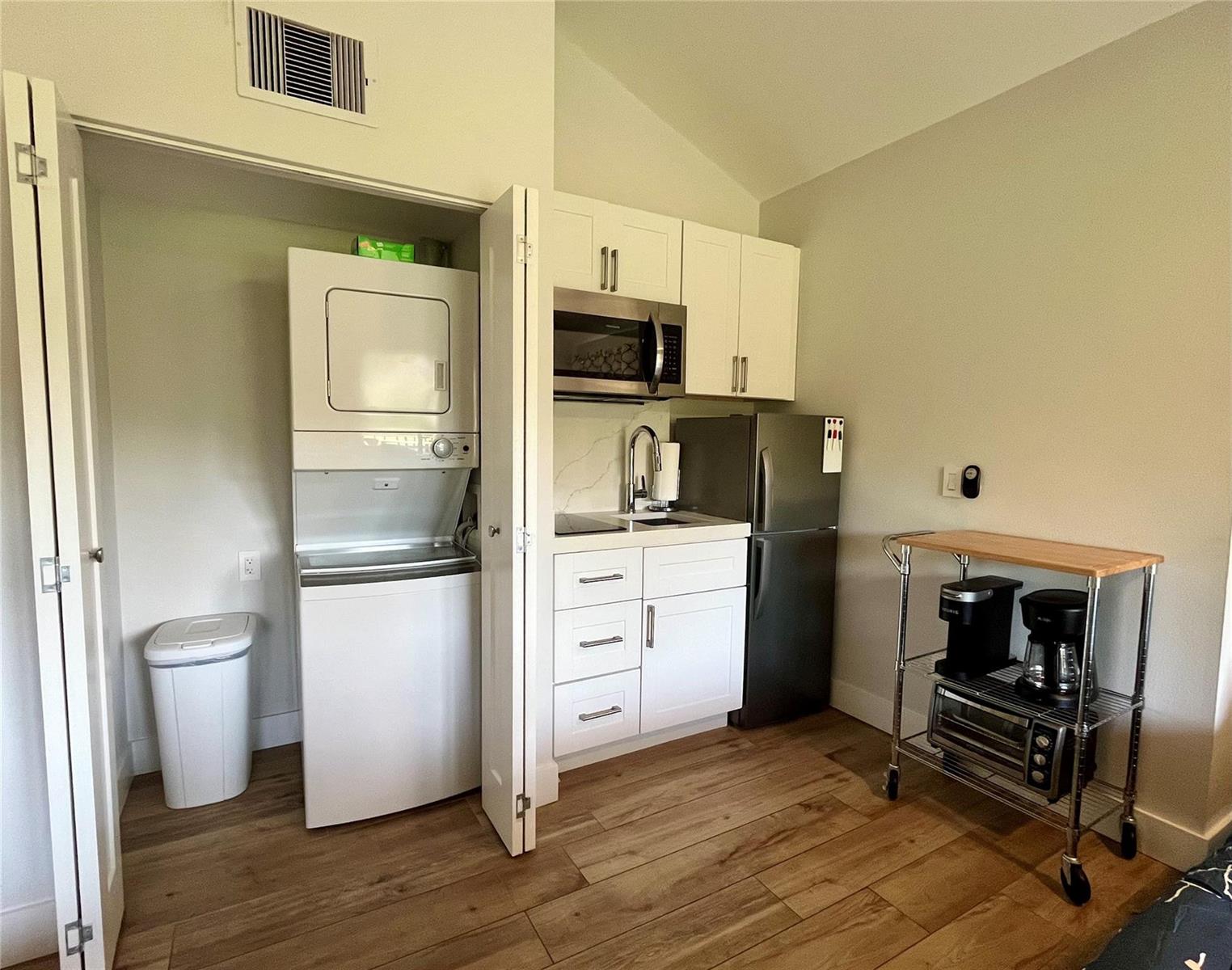 A small kitchenette features white cabinets, stainless steel appliances, and an adjacent stacked laundry unit — 11863 Wimbledon Circle # 536, Wellington FL 33414, WELLINGTON, FL